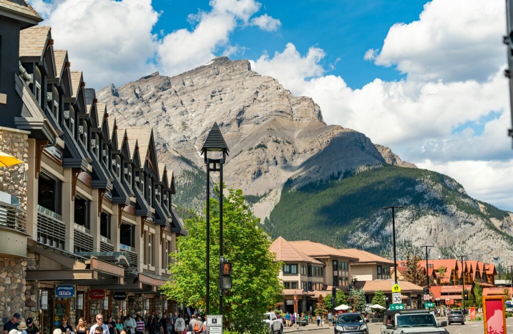 Charming Banff town street with iconic Canadian Rockies backdrop under a vibrant summer sky.