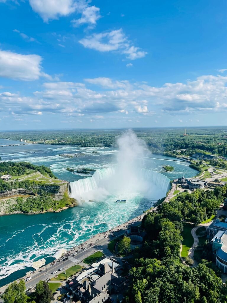 Stunning aerial view of Niagara Falls under a bright sky, showcasing its magnificent beauty.