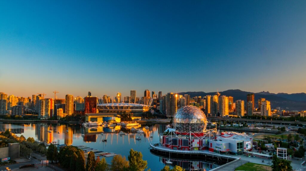 Vibrant sunset view of Vancouver's skyline, featuring Science World and cityscape reflections.