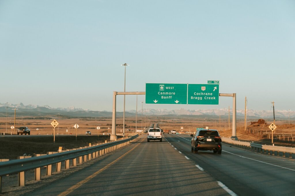 Highway drive with mountain view and road signs to Canmore and Banff.