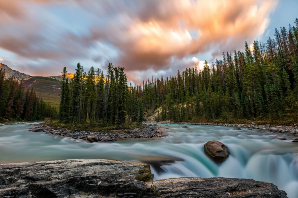 Breathtaking view of a waterfall in Jasper National Park under a vibrant sunset sky.