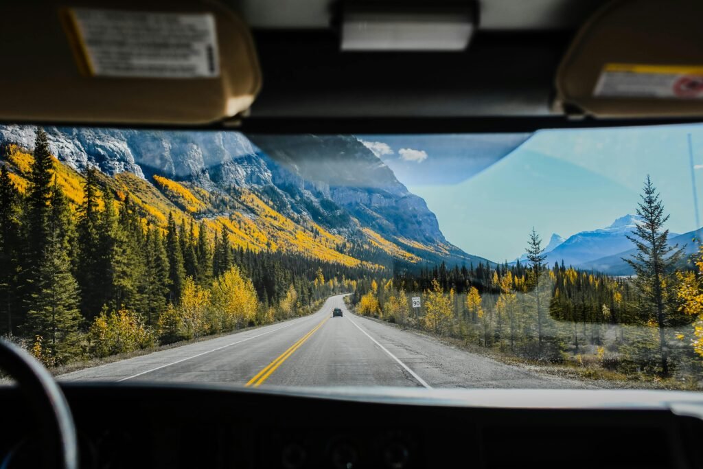 View from a car driving on a mountainous road surrounded by autumnal trees and scenic landscapes.