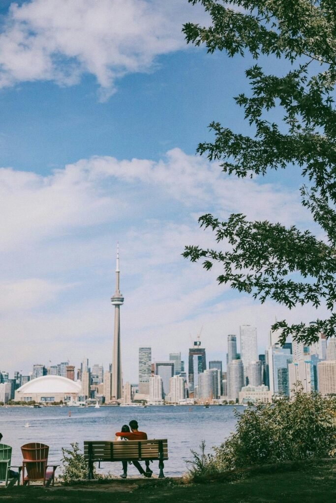 A couple sitting on a bench with a view of Toronto's skyline, featuring the CN Tower.