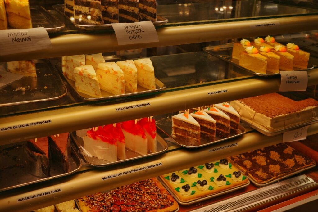 A variety of cakes and cheesecakes in a bakery display, showcasing diverse flavors.